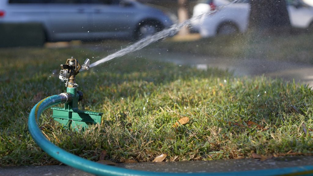 green sprinkler with water jet shooting out on lawn